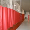 Row of red punching bags lining a training facility with white netting above and a gray floor.