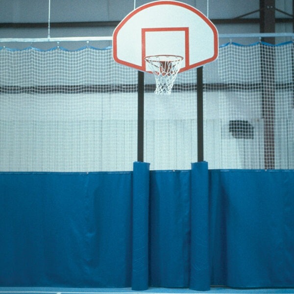 Basketball hoop with backboard mounted above blue padded wall in an indoor gym.