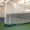 23955Z | National Sports Products Indoor gym with a white mesh netting enclosure forming a practice cage on green flooring and padded base.