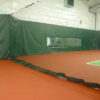 23955Z-8 | National Sports Products Indoor sports facility with green padded wall and protective netting, orange flooring, and a window into an adjacent room.